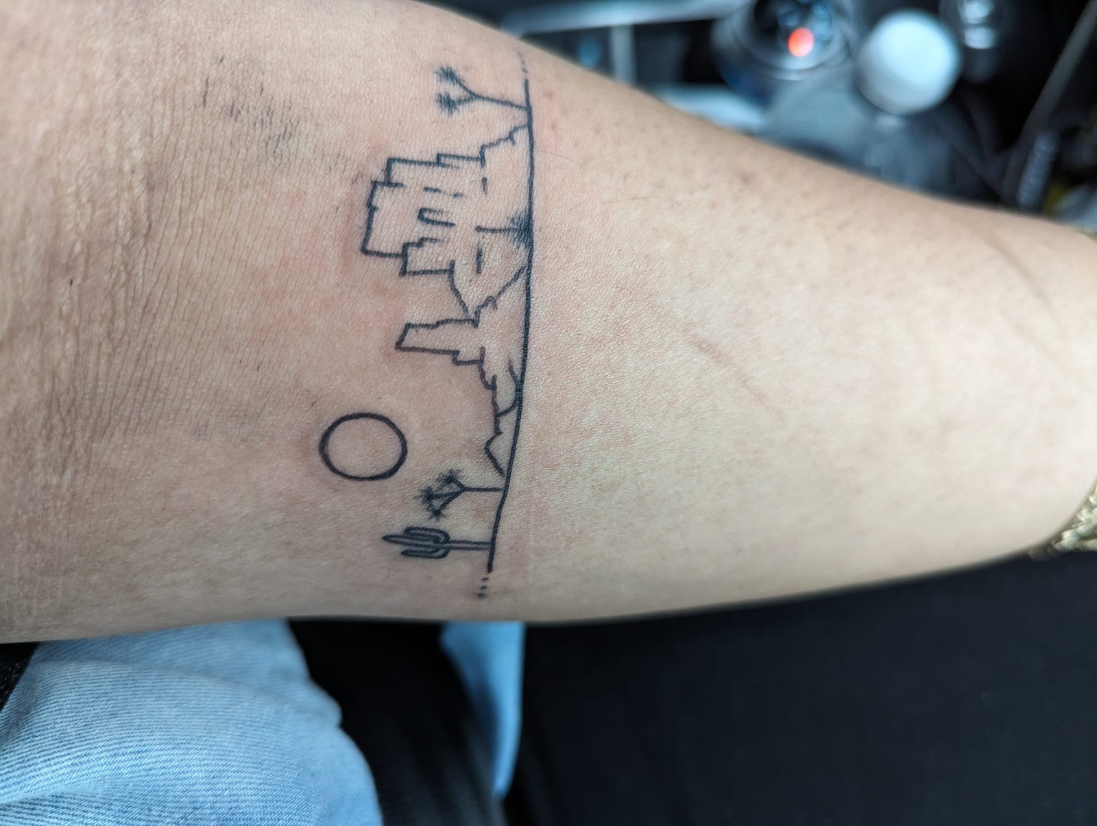Fine line desert horizon with a cactus and moon wrapped around an arm.