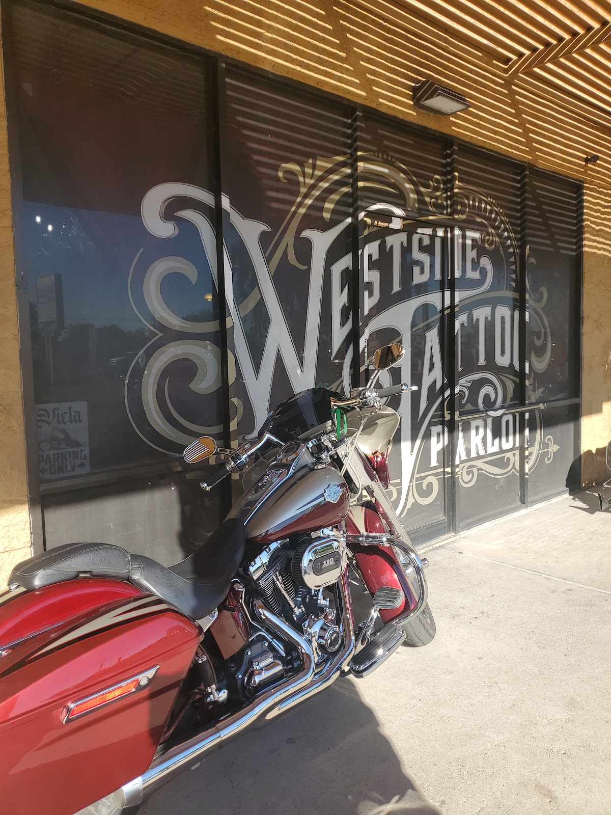 Ornate Westside Tattoo Parlor window lettering with a Harley parked out front.