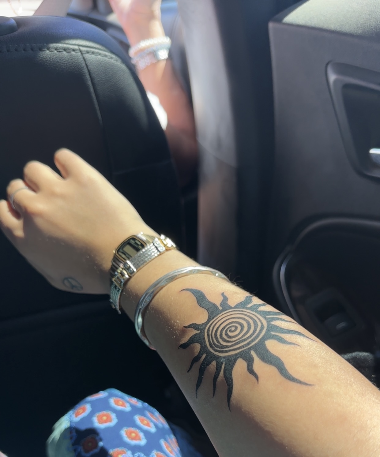 Tribal spiral sun tattoo on a forearm.